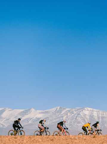 Cyclistes gravel devant les montagnes enneigées de l'Atlas